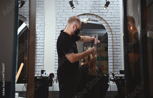 A professional hairdresser at work in beauty parlor, cutting hair of a business woman taking care of her long hair
