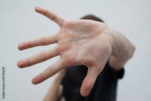 Young man protects himself with his hands