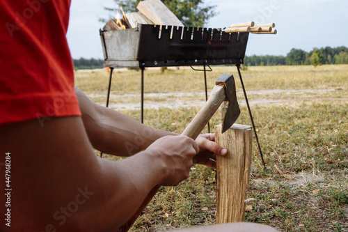 a man in a camping town chops firewood with an ax for a barbecue