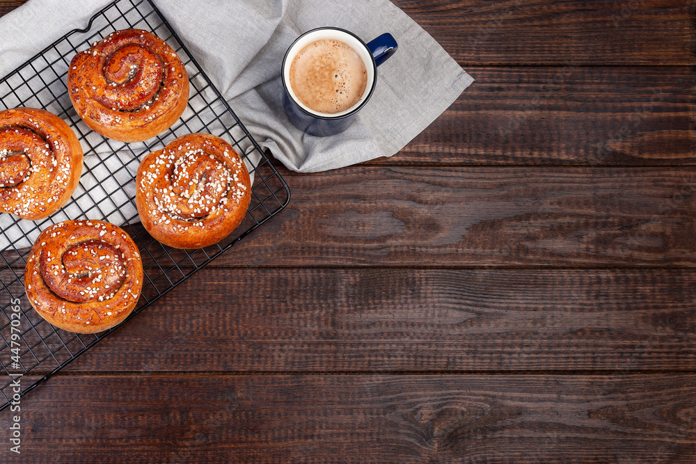 Traditional Swedish cinnamon buns Kanelbulle with cup of coffee or cappuccino, on wooden background, horizontal, top view, copy space Traditional Swedish cinnamon buns Kanelbulle with cup of coffee or cappuccino, on wooden background, horizontal, top view, copy space