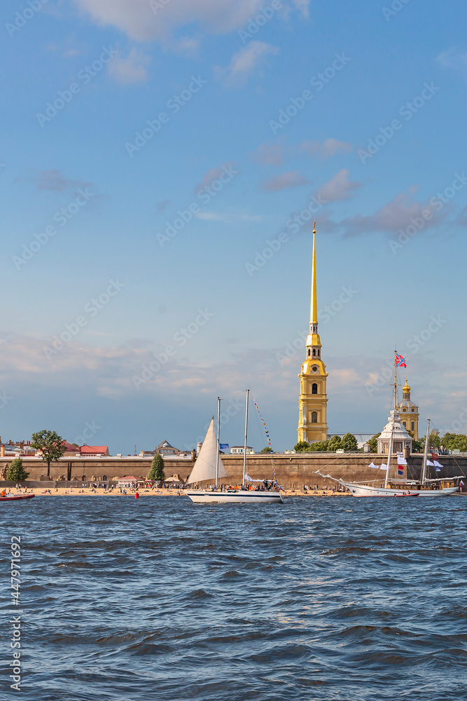 small sailboats and a white tourist ship are moored on the Neva at the walls of the Peter and Paul Fortress