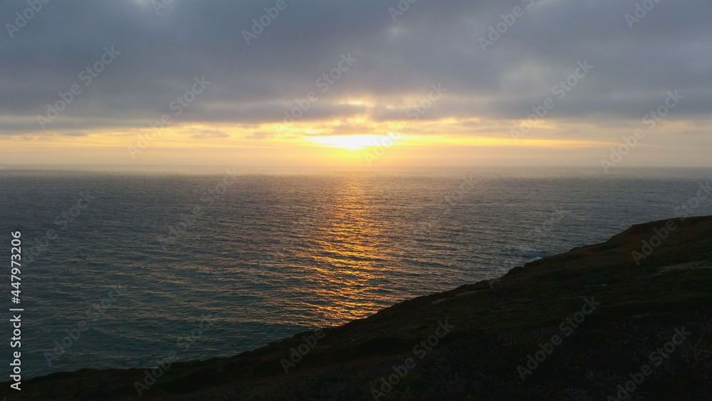 Gorgeous sunset over the ocean and a moody sky full of clouds at Ocean Beach in San Francisco, California