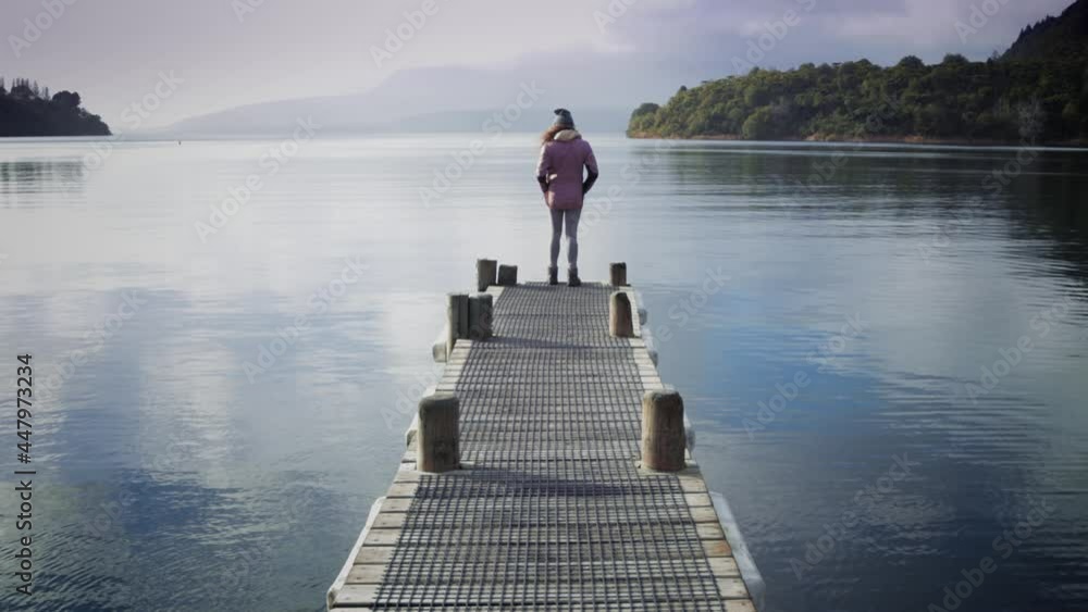 Lone girl stands at the end of a jetty with beautiful scenery, Rotorua, New Zealand Lone girl stands at the end of a jetty with beautiful scenery, Rotorua, New Zealand