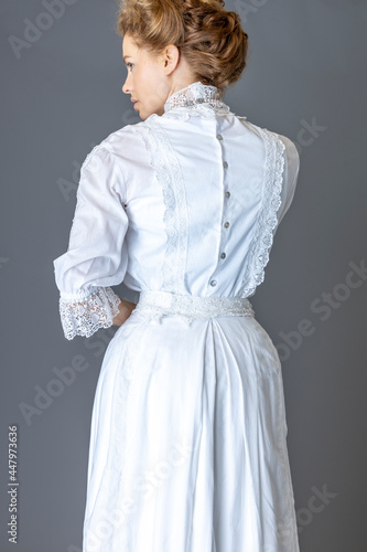 Fototapeta An Edwardian woman wearing a white lace trimmed blouse and skirt