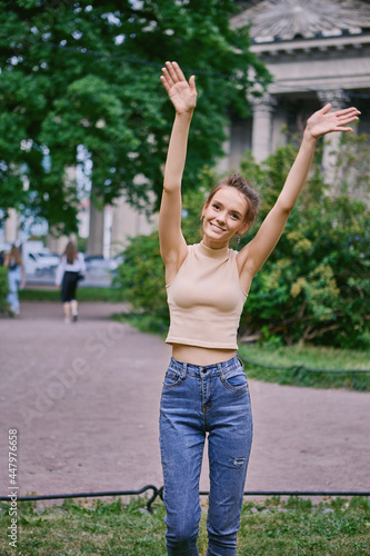 Slim happy young female walks in public park.