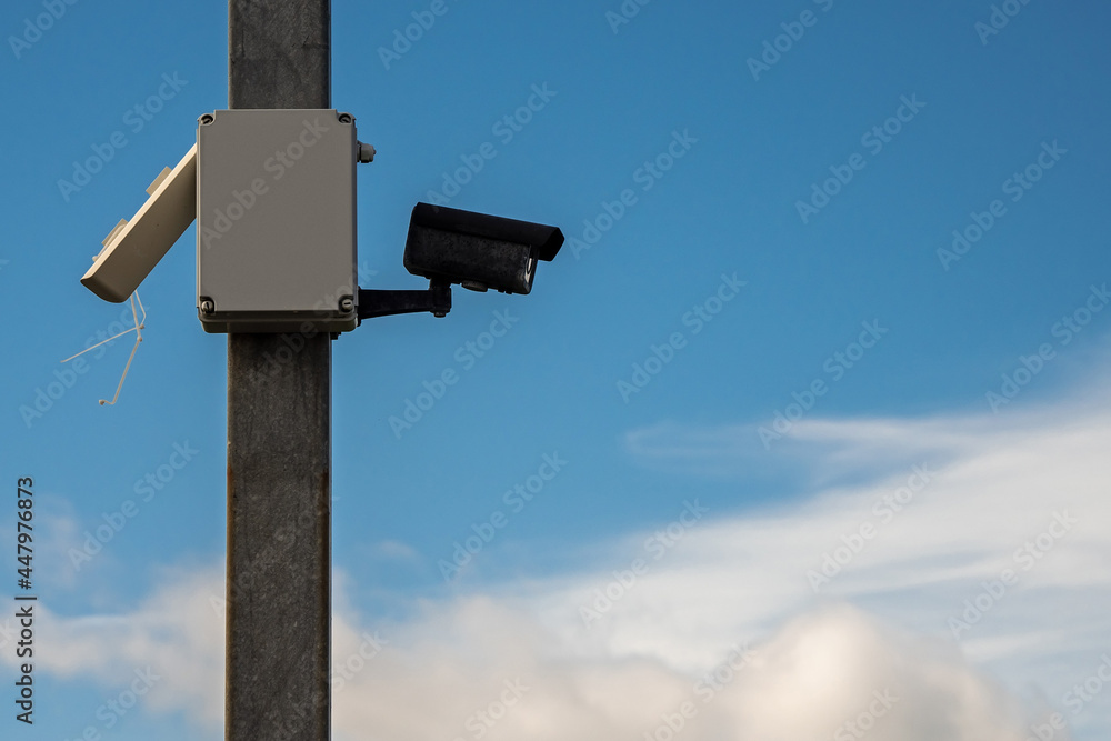 Security camera on a pole. Cloudy sky in the background Security camera on a pole. Cloudy sky in the background