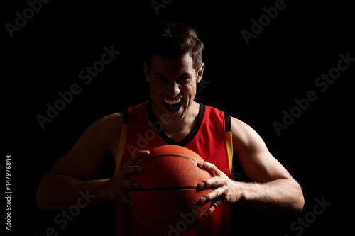 Basketball player with ball on black background © New Africa