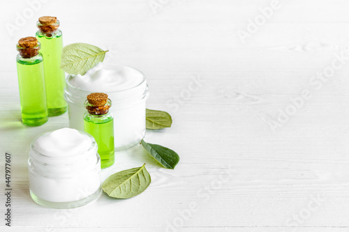 Tea essential oil in glass bottles with green leaves