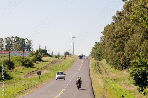 Busy route in a small town in Uruguay, with some windmills at the end of it photo
