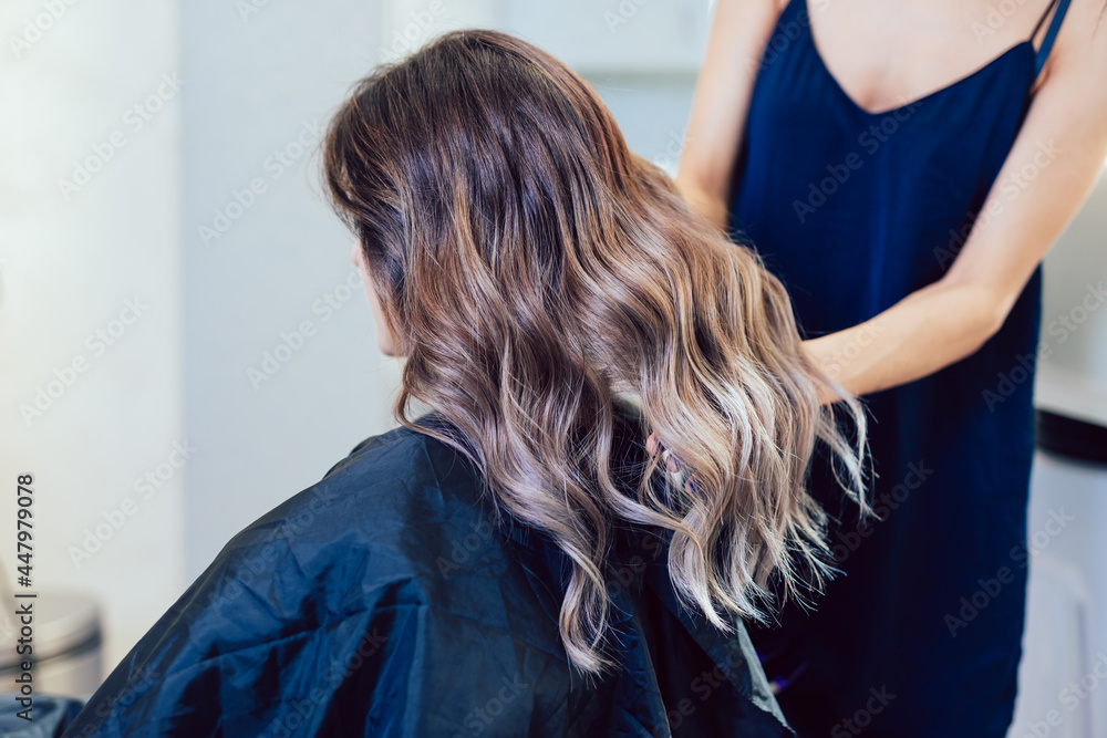 Fototapeta premium Beautiful hairstyle of a young woman after dyeing and highlighting hair in a hair salon.