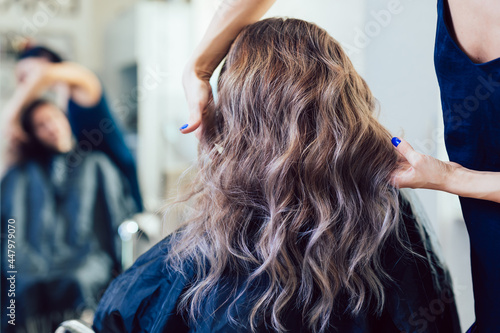 Beautiful hairstyle of a young woman after dyeing and highlighting hair in a hair salon.