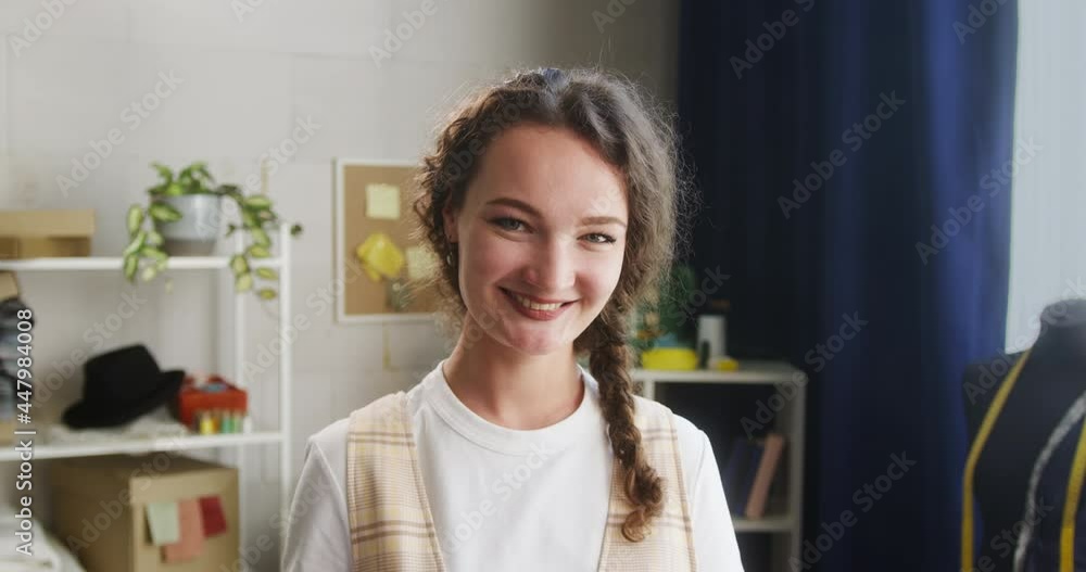 Young woman portrait, smiling dressmaker in workshop, female tailor standing looking in camera with smile. Shooting of happy seamstress close-up. Young woman portrait, smiling dressmaker in workshop, female tailor standing looking in camera with smile. Shooting of happy seamstress close-up.