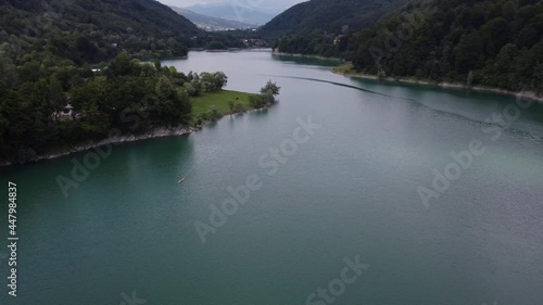 Aerial orbit shot of the natural landscape of trees that meet the lake at a cloudy sunset of Paltinu lake of Doftana Valley in Romania photo