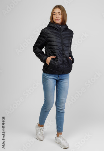 Young female model posing in black down jacket isolated on white background. Winter and autumn women down jacket mockup