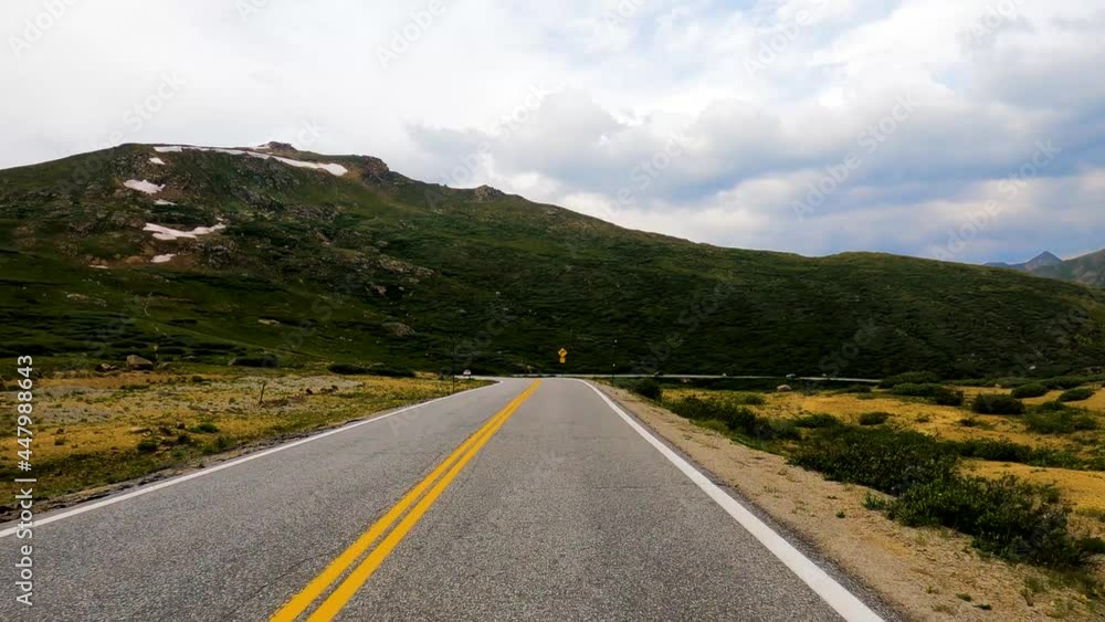 Driving through the Rocky Mountains above the timber line in summer with snow still on the peak Driving through the Rocky Mountains above the timber line in summer with snow still on the peak