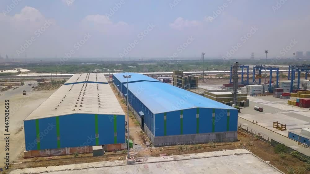 Aerial view towards a industrial storehouse, at a terminal marina - approaching, drone shot