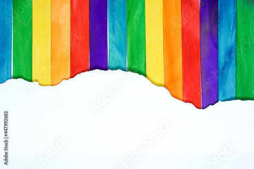 pride month background concept with ripped white mock up paper on colorful popsicle sticks,LGBTQ colors for background, rainbow colors,Pride community, flat lay and copy space concept.