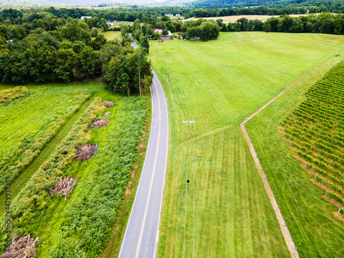 Aerial top view of a rural road along fields and farms