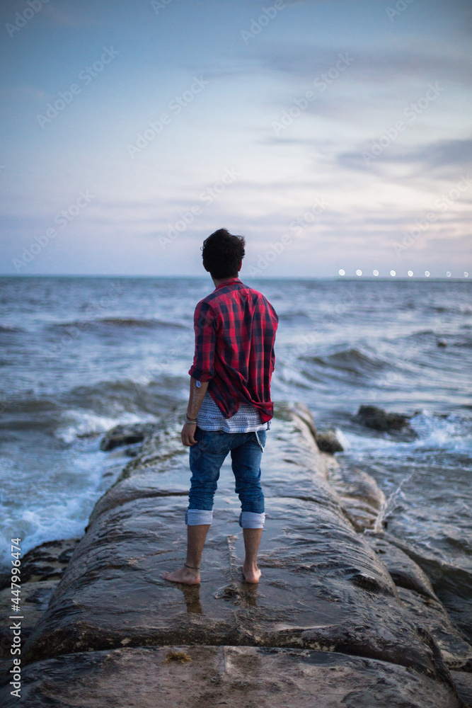 young man in plaid shirt in front of the sea
