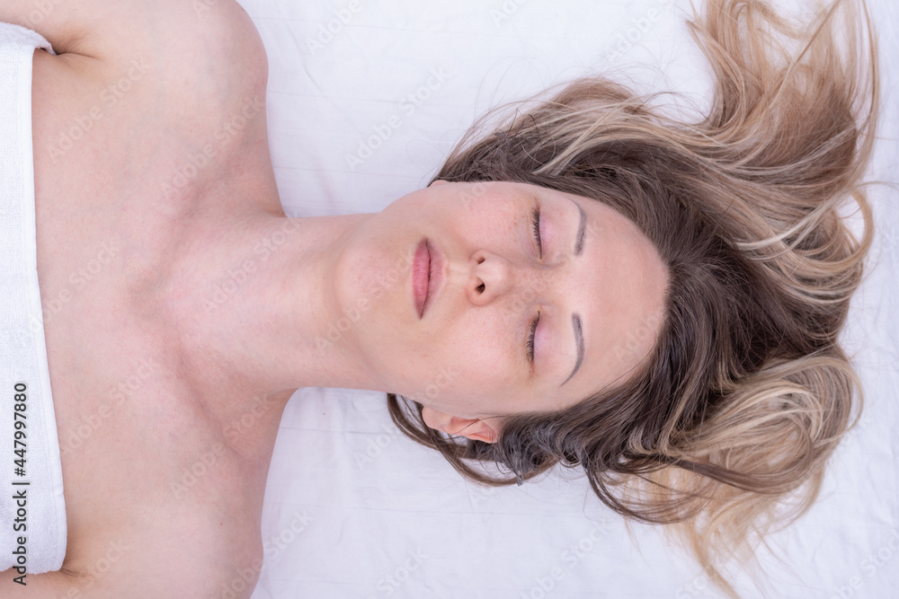 Portrait of a beautiful caucasian woman enjoying a massage with closed eyes and long blond hair in a spa salon. Portrait of a beautiful caucasian woman enjoying a massage with closed eyes and long blond hair in a spa salon.