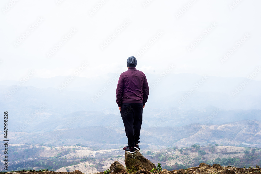 man standing on a ridge looking at the mountains in the background