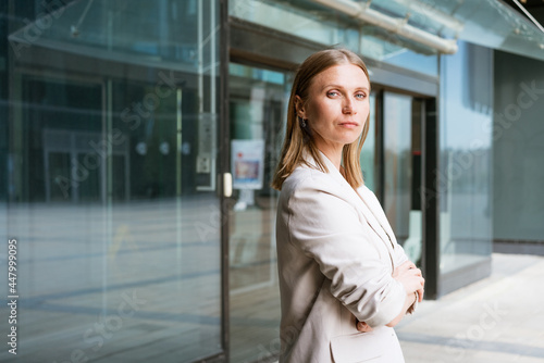 Business woman portrait Crossed arms. Happy successful professional portrait near an office building. Young caucasian business woman with clasped hands standing outside. Female business leader concept