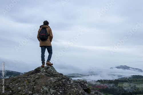 young man on the top of a mountain on a foggy day