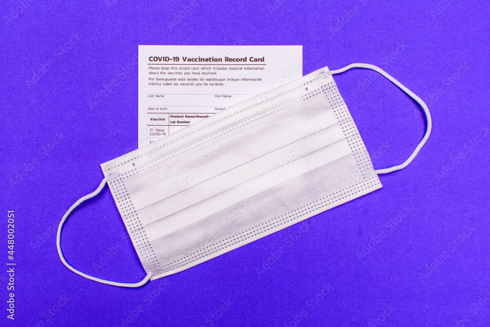 Covid-19 vaccination record card and white hygiene face mask for virus infection risk people preparing for vaccine injection at hospital to get safe life against disease outbreak. Covid-19 vaccination record card and white hygiene face mask for virus infection risk people preparing for vaccine injection at hospital to get safe life against disease outbreak.