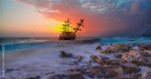 Sailing ship in storm sea at sunset clouds