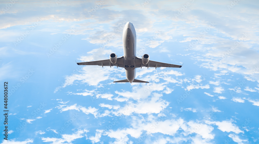 Naklejka premium White passenger airplane under the amazing clouds - Travel by air transport
