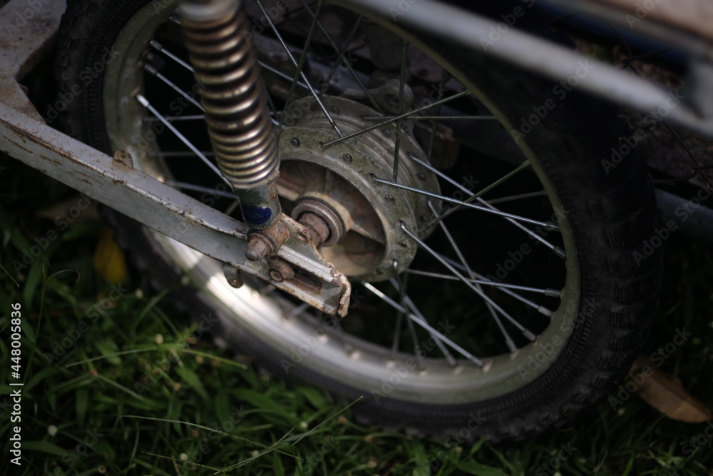 Obraz premium An old motorcycle wheel parked in the park