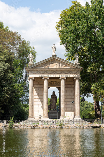 Lake and building in Borghese garden with blue sky, clouds and trees