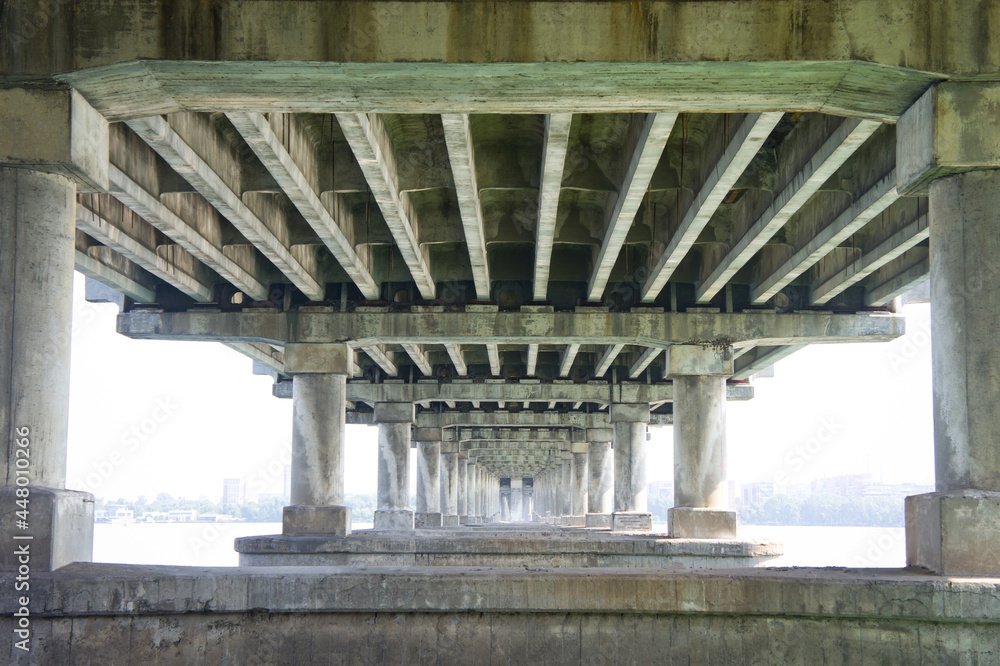 Reinforced concrete supports of a wide road bridge, taken from the lower angle.