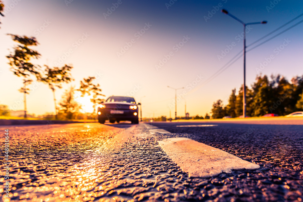 Sunset after rain, the car on the highway. Wide angle view of the level of the dividing line Sunset after rain, the car on the highway. Wide angle view of the level of the dividing line