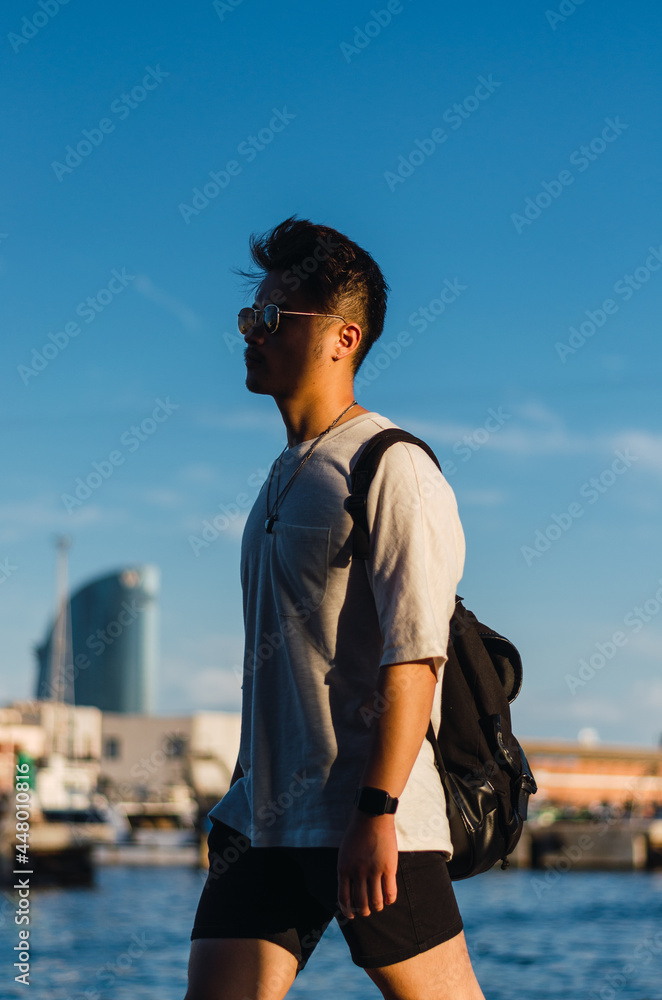 Portrait of young handsome Chinese man in front of Barcelona port and sea