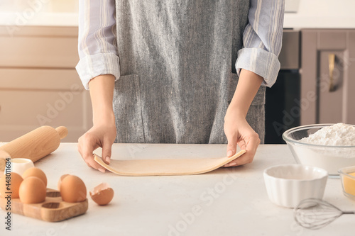 Woman with puff dough and ingredients in kitchen