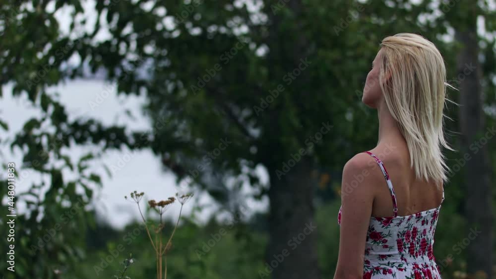 A hipster woman standing alone with a front view reflection of trees. An unhappy lady observing in tranquility with a thoughtful mind. A woman standing in wind weather with an unhappy expression. A hipster woman standing alone with a front view reflection of trees. An unhappy lady observing in tranquility with a thoughtful mind. A woman standing in wind weather with an unhappy expression.