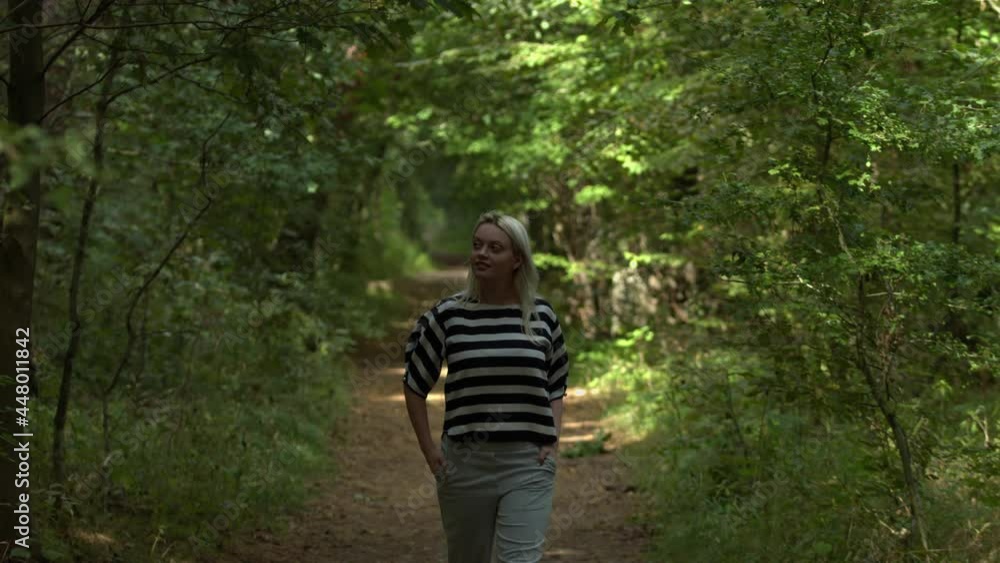 A young adult lady walking alone in the park expressing emotional freedom with a smile. a lonely lady walking in a greenery park look up around the sunlight and express joy and confidence. A young adult lady walking alone in the park expressing emotional freedom with a smile. a lonely lady walking in a greenery park look up around the sunlight and express joy and confidence.