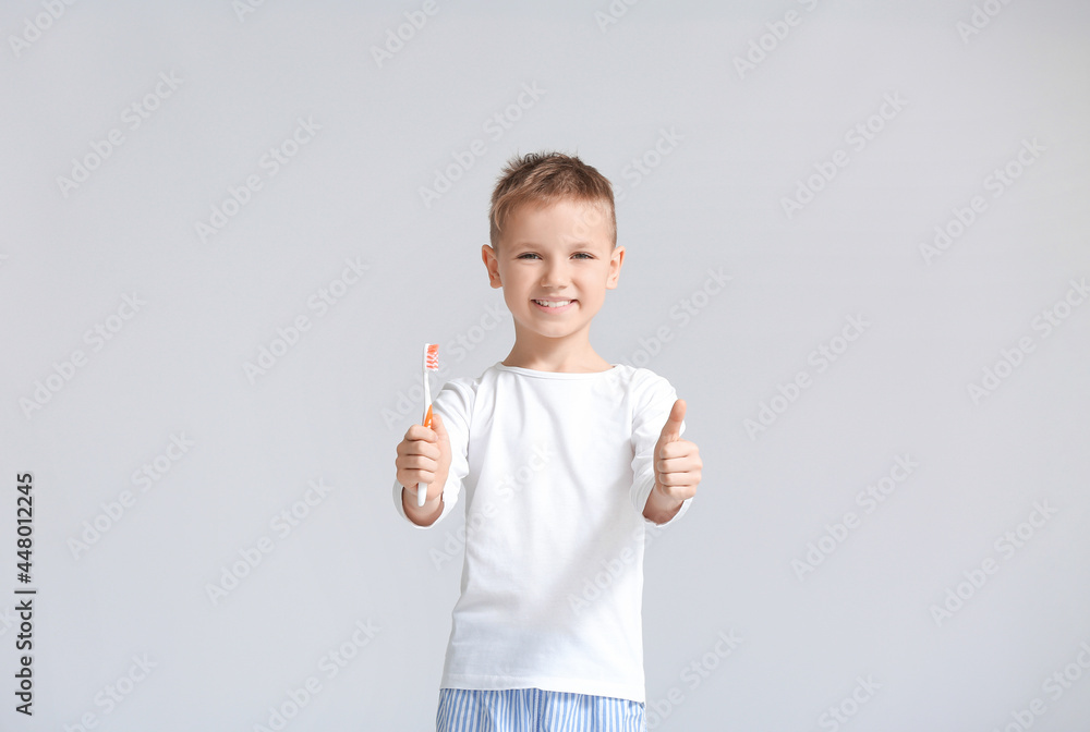Little boy with tooth brush showing thumb-up on grey background Little boy with tooth brush showing thumb-up on grey background