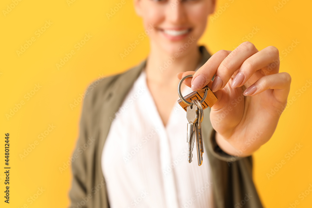Fototapeta premium Happy young woman with key from house on color background, closeup