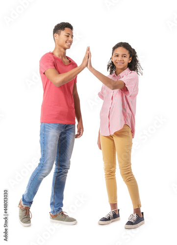 African-American brother and sister giving each other high-five on white background