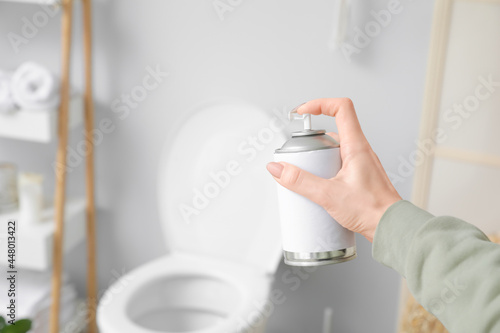 Woman spraying air freshener in bathroom photo