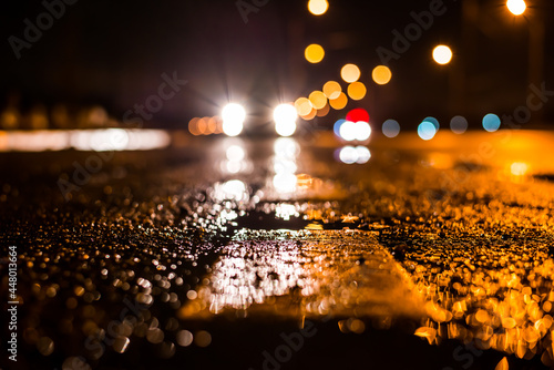 Rainy night in the big city, the car traveling towards the headlights illuminate the road. Close up view from the level of the dividing line