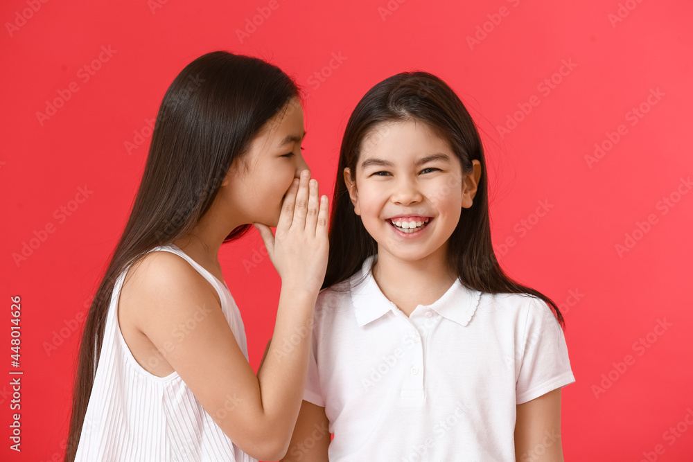 Little girl telling sister her secret on color background Little girl telling sister her secret on color background