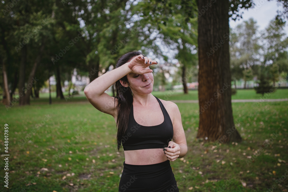 Young woman tired after workout wipe off sweat sports in the park Young woman tired after workout wipe off sweat sports in the park