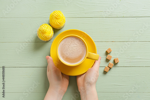 Hands holding yellow coffee...