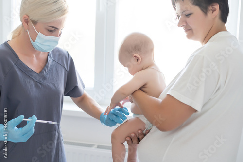 Pediatrician doctor with syringe, tense mother and baby