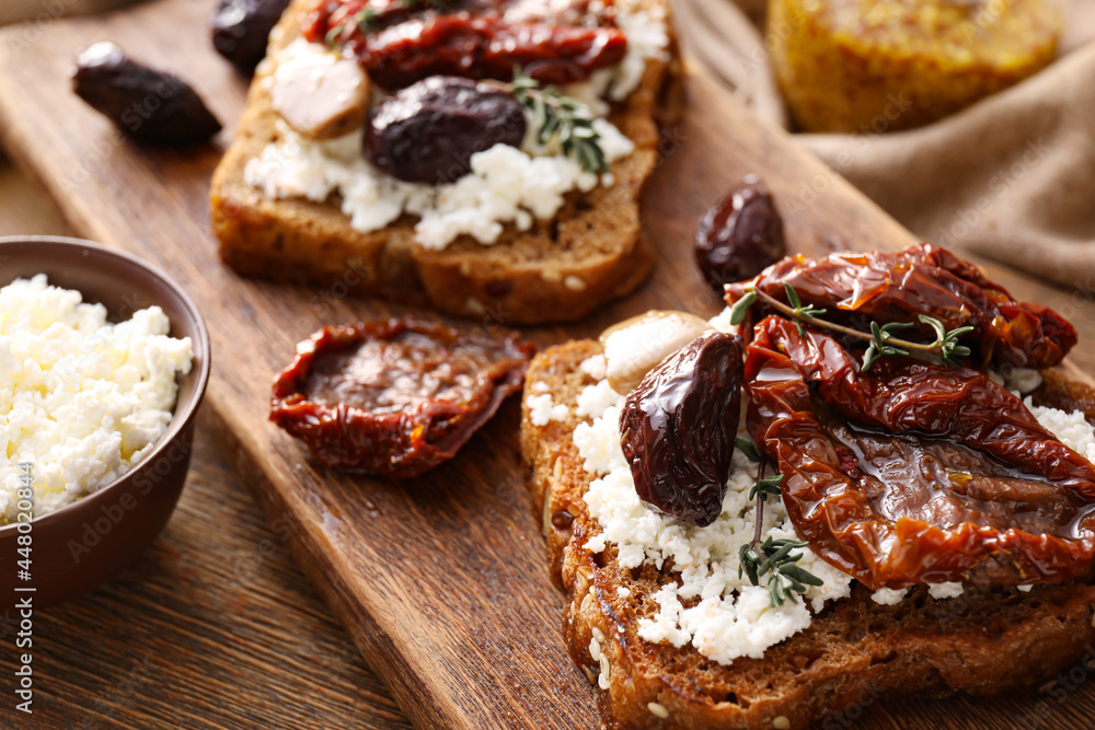 Tasty bruschettas with cheese, sun-dried tomatoes and dates on table, closeup Tasty bruschettas with cheese, sun-dried tomatoes and dates on table, closeup