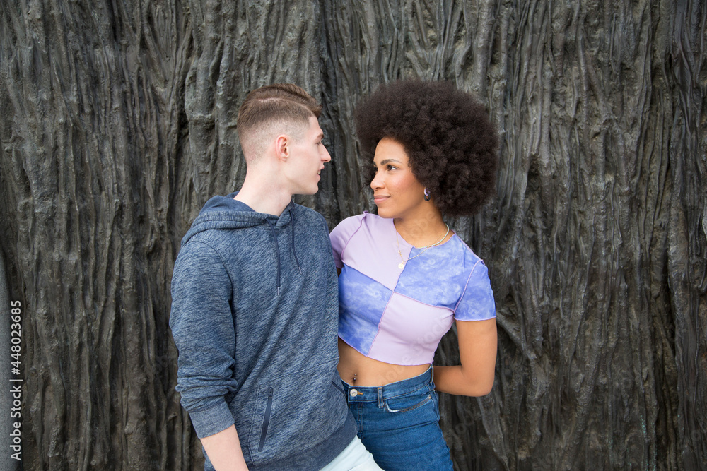 portrait young multiethnic couple Caucasian man and afro woman looking at each other over dark background