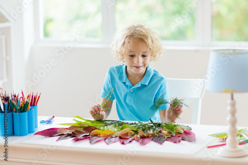 Child creating picture with colorful leaves.